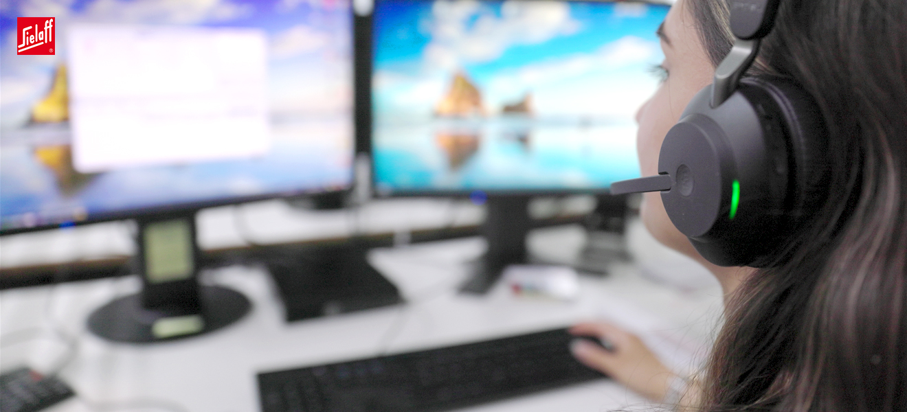 Eine Industriekauffrau vor zwei Bildschirmen