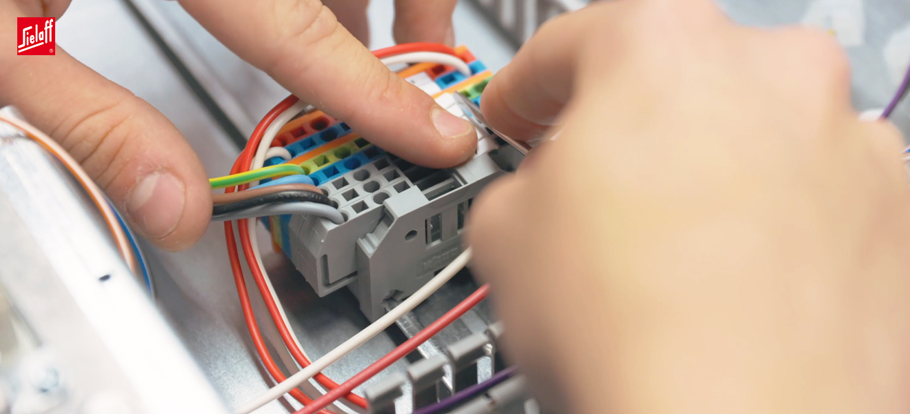 Ein Elektroniker für Betriebstechnik bei der Arbeit mit Kabeln