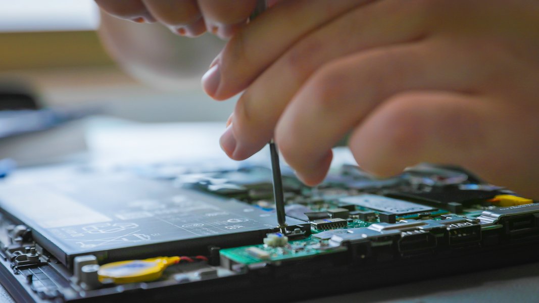 Ein Fachinformatiker schraubt an einer Platine